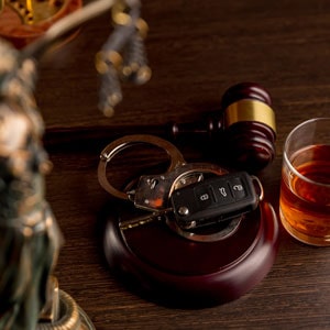 A judge's gavel, car key, handcuff and glass of wine on a table